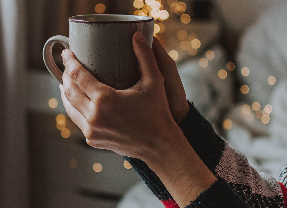 Two hands holding a mug filled with a hot winter beverage
